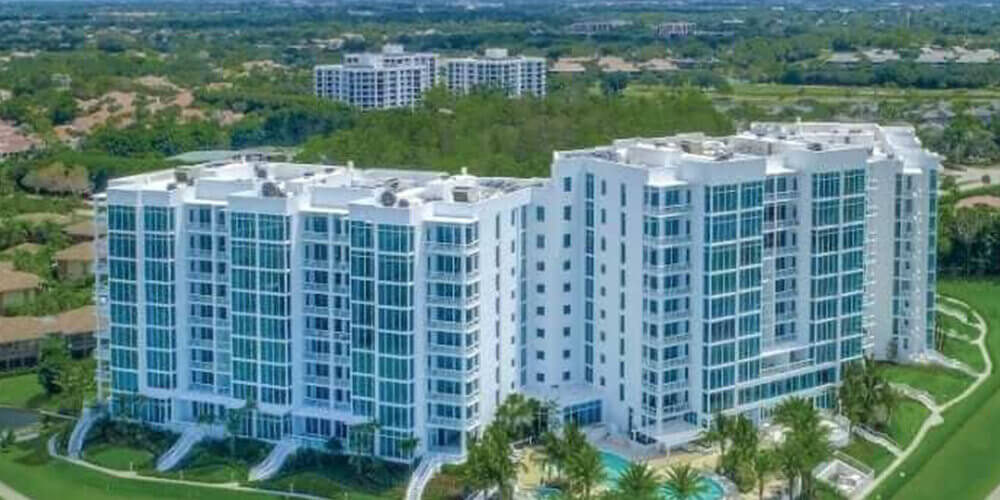 Modern white apartment buildings with surrounding greenery.