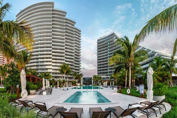 A large pool with chairs around it and palm trees.