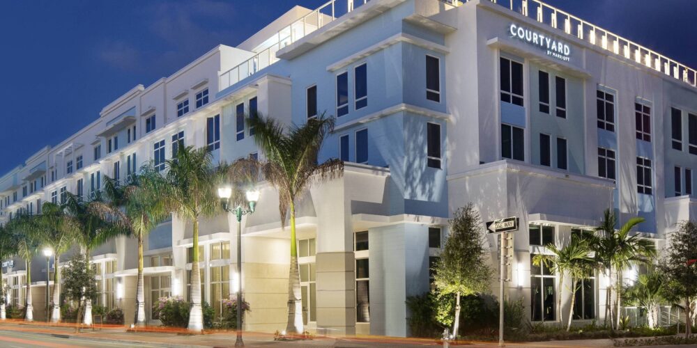 A building with palm trees and lights on the side.