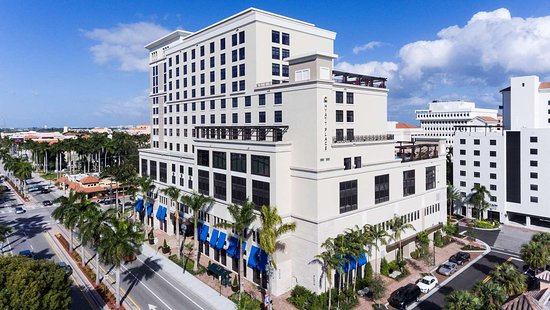 A large white building with palm trees in the background.